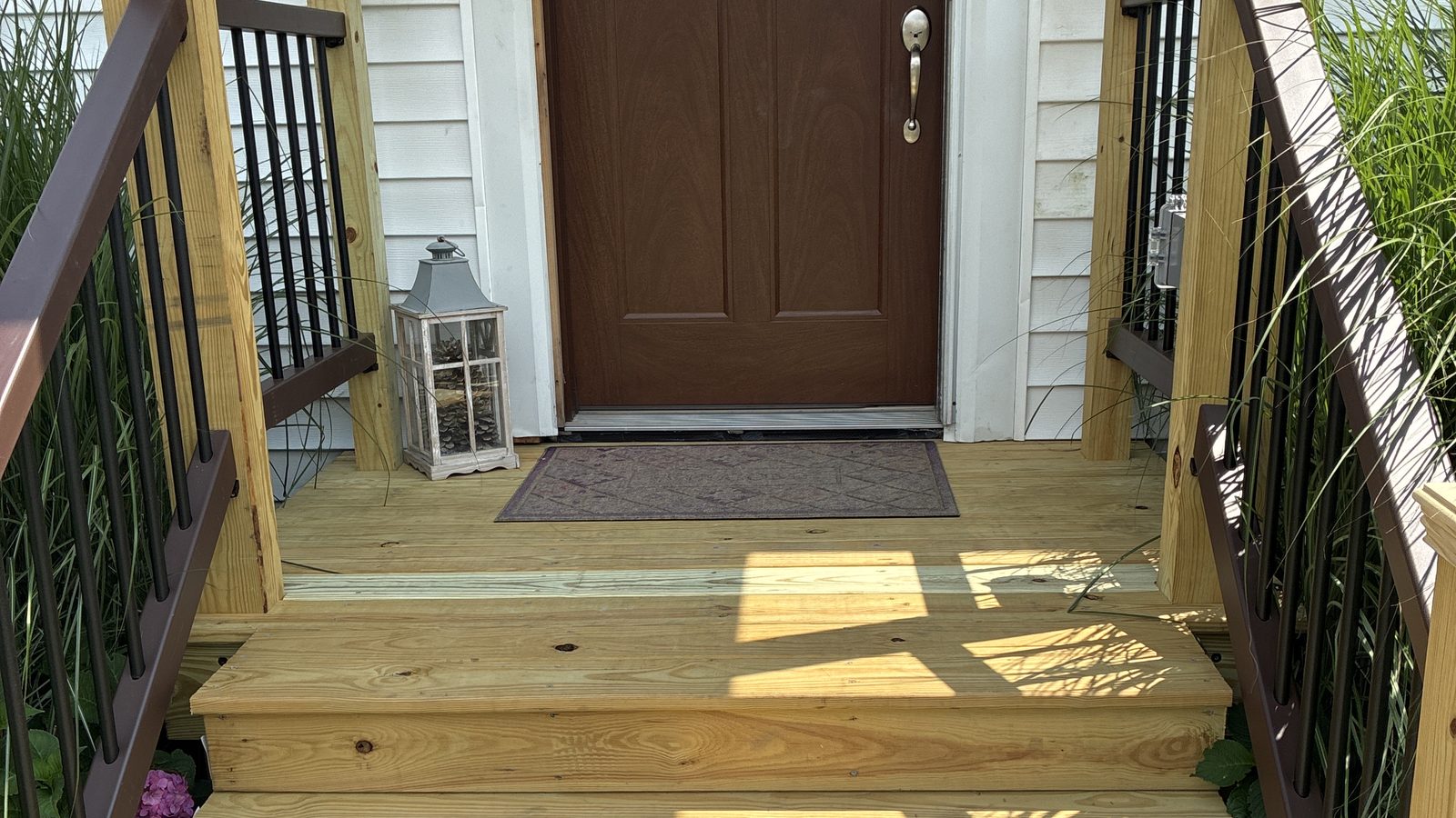 Rebuilt front porch with treated decking and composite railings — the kind of exterior work seasonal checks protect