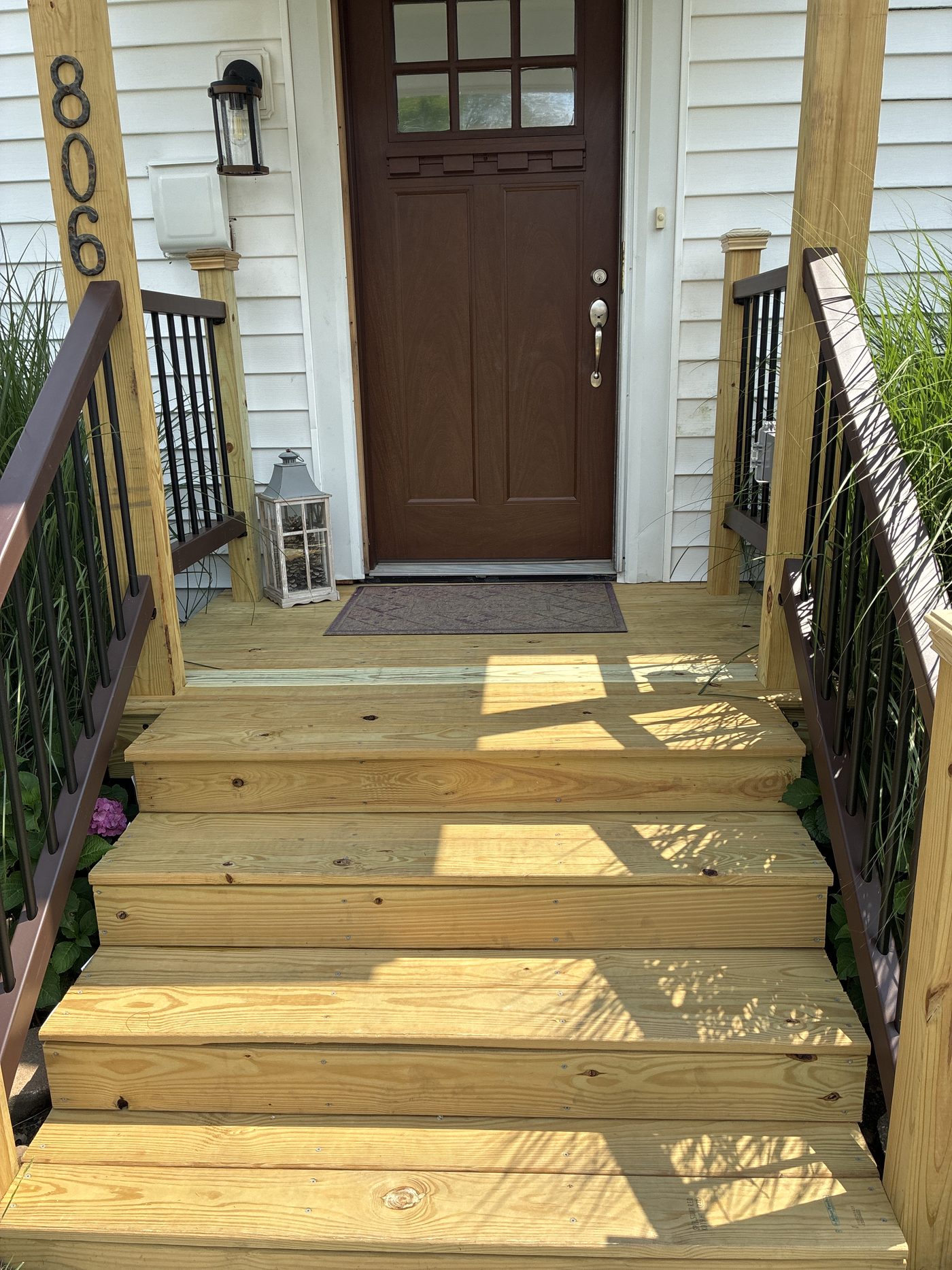 Rebuilt front porch with treated decking, wide steps, and composite railings with black balusters